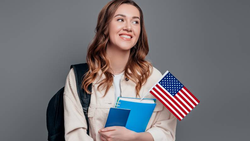 Happy girl student holding backpack, book, notebook, passport and USA flag